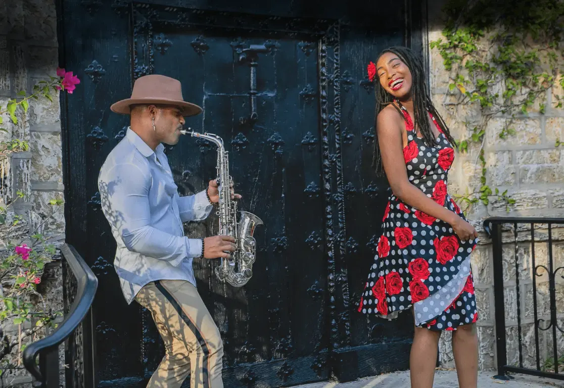 Saxophonist und Tänzerin im roten Kleid vor einer alten Tür in Havanna